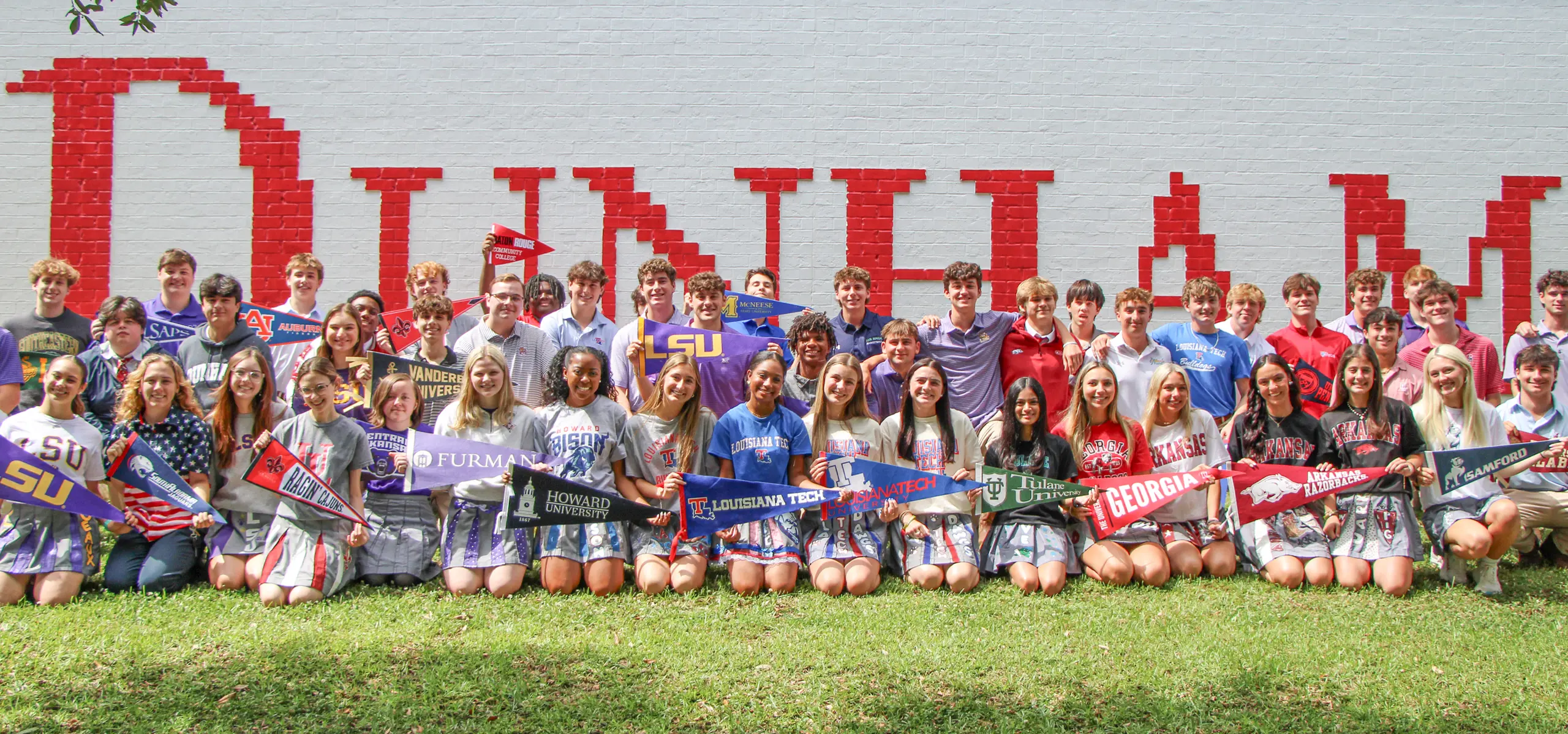 Group of seniors holding up college pennants.