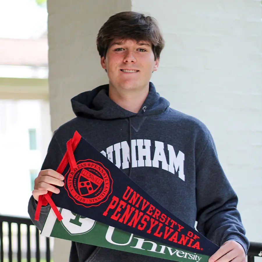 Dunham senior holding college pennants.