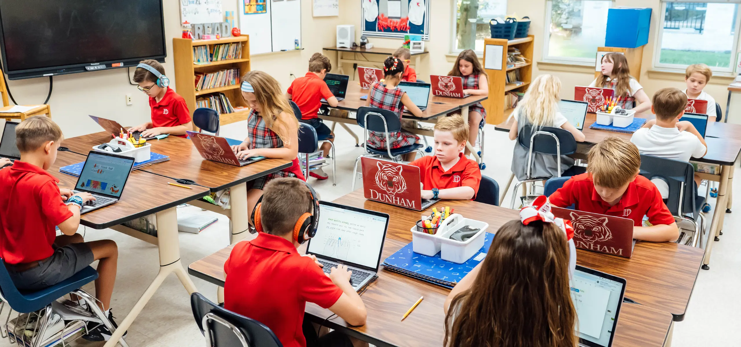 Dunham lower school students in classroom learning with Apple MacBook laptops.