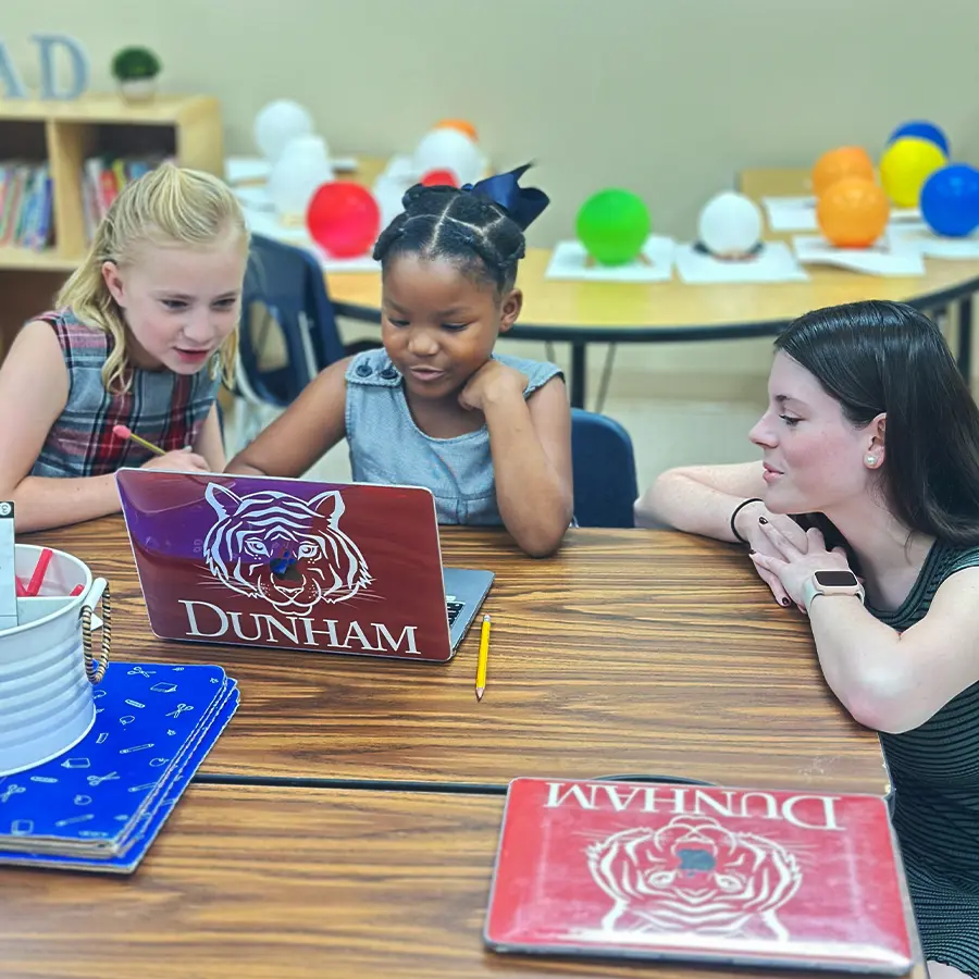 Two lower school students learning from LSU student.